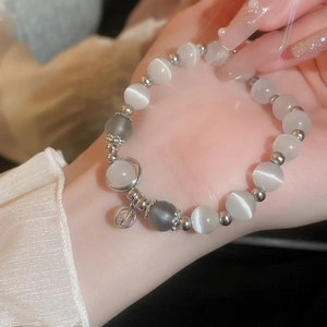 Detail of vintage cat eye stone beaded bracelet with hollow sphere charm on woman's wrist