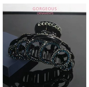 Macro shot of large black resin hair claw clip with blue and white sparkling rhinestones