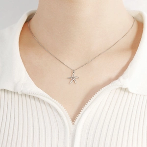 Gros plan détaillé d'un collier avec pendentif étoile de mer porté sur un pull blanc