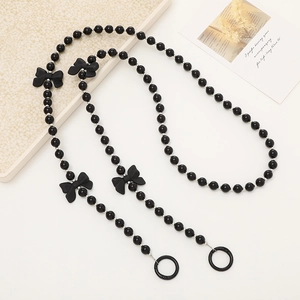 Beaded crossbody phone chain with black round beads and ribbon bow charms on white
