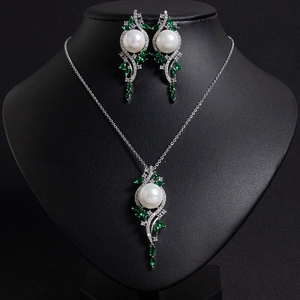Luxurious silver jewelry set with white pearls and emerald stones on a display mannequin