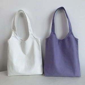 Detail of solid color canvas tote bags in white and lavender with wide handles