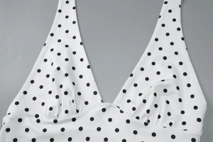 Detailed view of polka dot halter top showing white fabric with black dots and fine stitching