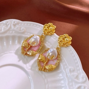 Detailed macro view of vintage gold rose earrings with pink pearls on a white plate