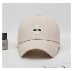 Close-up of beige cotton baseball cap featuring a round BRTXN embroidered patch design