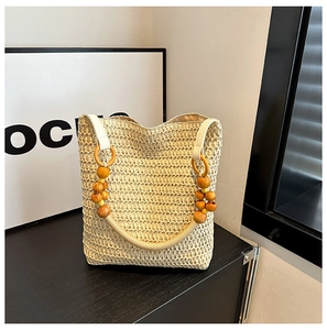 Detailed view of beige straw tote bag with decorative natural wooden bead handles