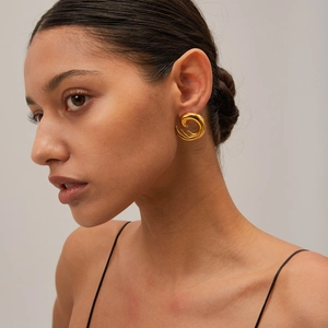Close-up of elegant gold spiral twisted earrings on model with high-polished metal finish