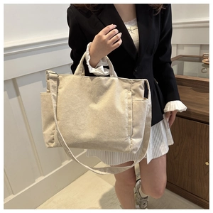 Beige corduroy tote bag styled with a professional black blazer and white pleated skirt