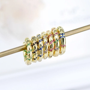 Macro shot of s925 silver hoop earrings with vibrant colorful zircons and golden finish