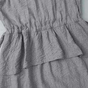Détail d'une robe grise présentant une texture plissée et des volants superposés