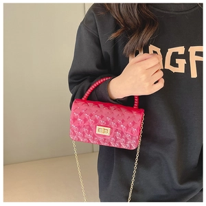 Detail of red quilted jelly bag with gold lock and beaded handle worn by a model