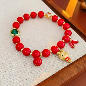 Détail du bracelet en perles rouges avec pendentif dragon doré et perle à facettes verte