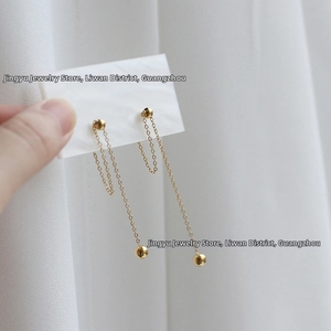 Detail of elegant gold drop earrings with delicate chains and polished round beads