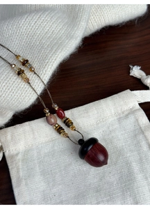 Detailed view of hazelnut pendant necklace with stone beads and warm wood textures