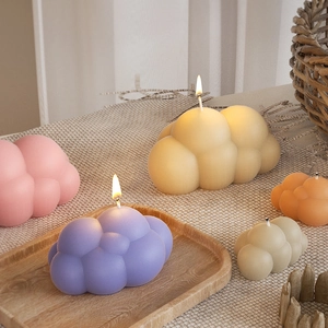 Dettaglio di candele profumate a forma di nuvola 3D colorate in ambiente accogliente
