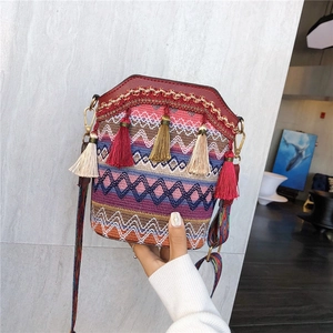 Ethnic woven bucket bag with geometric wave pattern and vibrant red tassels