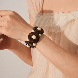 Detailed view of dark brown coconut shell discs and beige beads on a vintage stretch bracelet
