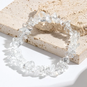 Macro shot of clear natural quartz crystal beads on a textured stone surface
