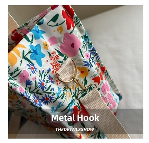 Close-up of durable golden metal hooks and woven strap on a floral tote bag