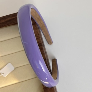 Detail of a slim purple headband with glossy finish and soft velvet lining on wood