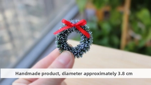 Macro shot of 3.8cm mini handmade Christmas wreath with red bow and snow effect