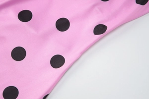 Gros plan sur un tissu rose à pois noirs avec une texture lisse et élastique