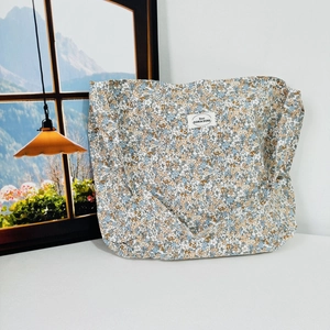 Close-up of floral canvas tote bag with Best DORIA DORE label on a white surface