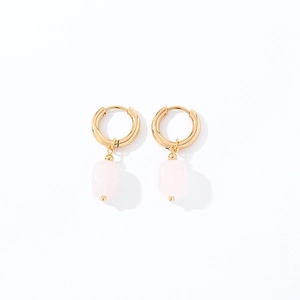 Macro detail of geometric natural stone earrings with gold finish and pink pendants
