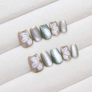 Cat eye press-on nails set with nude pink, mint green daisy designs and gold edges