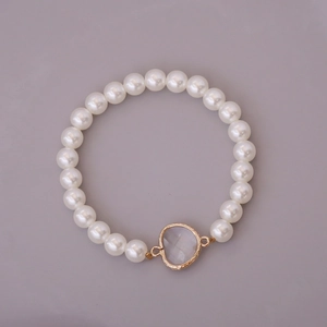 Detail of white glass pearls and heart-shaped transparent stone on elastic bracelet