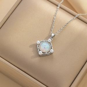 Silver stainless steel planet necklace with opal and pearls on a beige jewelry box
