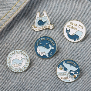 Detailed set of five whale enamel pins on blue denim, featuring Save the Ocean slogans