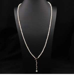 Detail of a long Y-shaped natural pearl necklace on a black neck model with gold accents