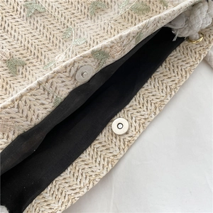 Handwoven straw tote bag with green leaf embroidery and magnetic clasp closure