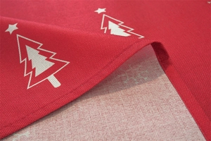 Detail of red polyester tablecloth featuring white Christmas trees and stitched edges