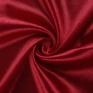 Macro shot of elegant wine red satin fabric showing smooth texture and spiral folds