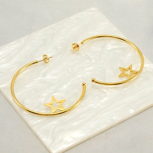Fashionable gold stainless steel hoop earrings with hollow star charms on marble base