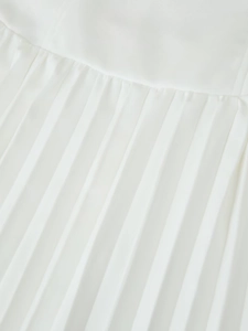Detailaufnahme der eleganten weißen Plisseestruktur mit seidigem Finish am langen Kleid