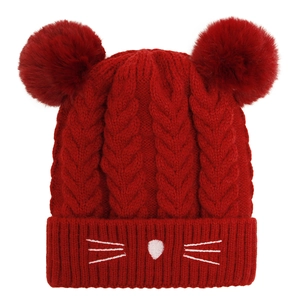 Detailed knit texture of a dark red baby hat with fluffy pom-poms and cat embroidery