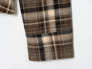 Close-up of brown plaid shirt cuff showing flannel fabric texture and stitching detail