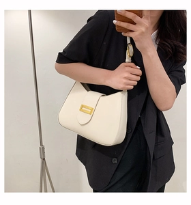 Detail view of cream-white baguette bag featuring golden buckle and smooth leather