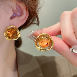 Detailed close-up of a geometric amber resin bead earring in a gold irregular metal frame