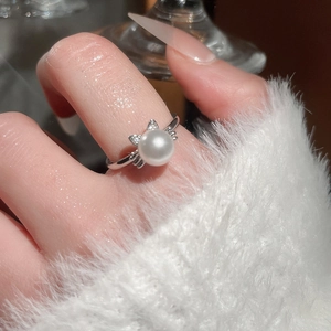 Detail of elegant cat-shaped ring with white pearl and sparkling zircon on finger