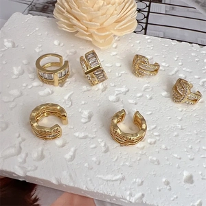 Set of 6 gold-plated ear cuffs with clear crystals on a white textured background