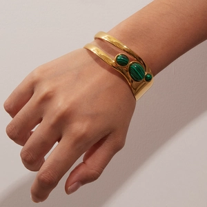 Detail of a vintage-style gold-plated open cuff bracelet with three green malachite stones