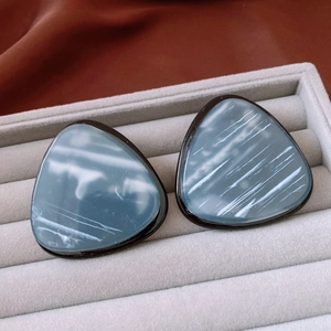 Macro detail of vintage blue resin triangle earrings with marble texture and black frames