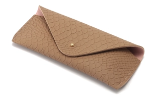 Macro detail of brown crocodile embossed faux leather glasses case with gold button