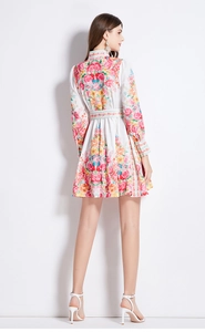 Detail of white floral A-line dress featuring vibrant red roses and back waist belt design