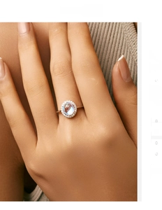 Detail of 2-carat oval moonstone ring with zircon halo on silver band worn by model