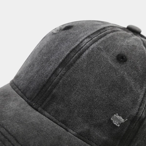 Dettaglio ravvicinato del cappello da baseball in denim lavato con rifiniture usurate e fori